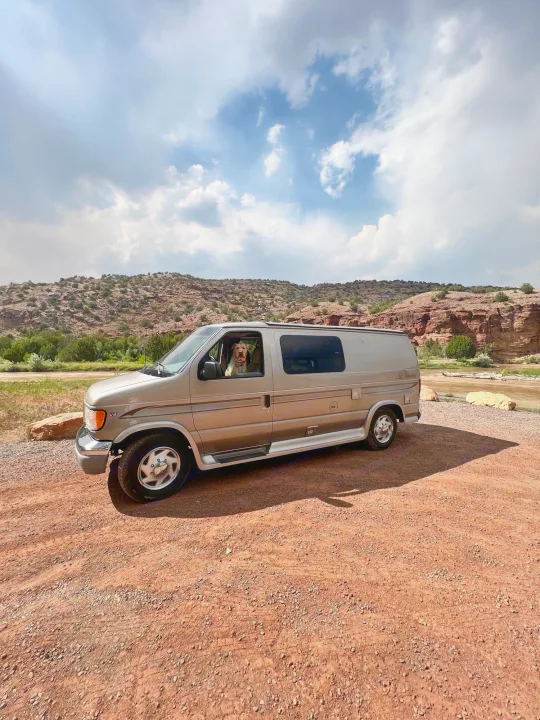 Enjoying a scenic stop! This dog is loving the views from an RV rental van parked by red cliffs & a river.. Ford Pleasure Way Xl Rd Widebody 2002