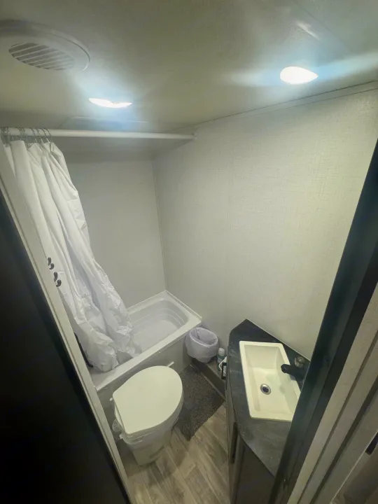 Compact RV rental bathroom with shower, toilet, and sink. Brightly lit, functional space for your travels.. Dutchmen Kodiak SE 2024