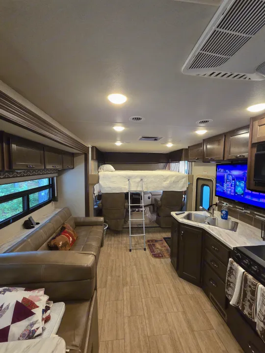 Inside this rv rental: a comfy living area with sofa, kitchen, and bunk bed for your road trip adventures.. Thor Freedom Traveler 2020