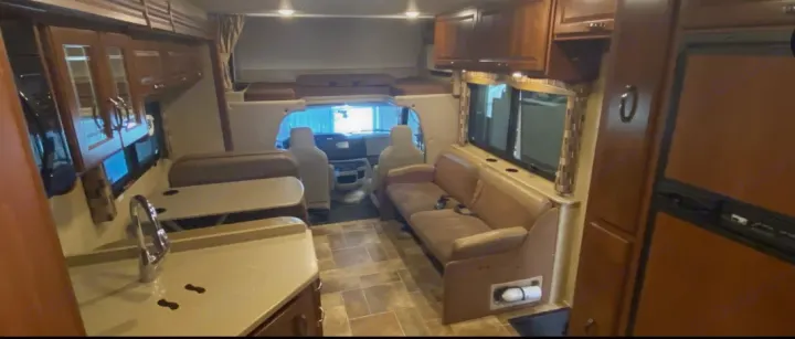 Spacious RV rental interior: kitchen with sink, dinette, couch, and front cab area. Light wood cabinets.. Thor Chateau 2016