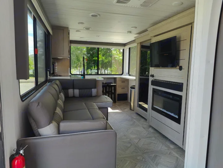 Spacious RV rental interior with L-shaped sofa, kitchen, large windows, TV, and electric fireplace. Perfect for your next adventure!. Forest River Salem Cruise Lite 2024