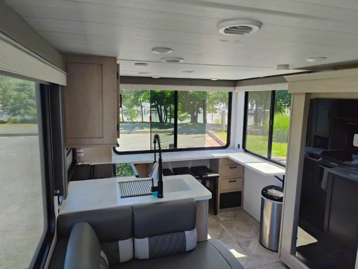 RV rental interior featuring a modern kitchen, comfortable seating, and large windows revealing a scenic waterfront view.. Forest River Salem Cruise Lite 2024