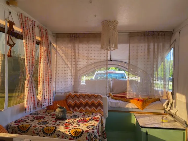 Warm RV rental interior: boho decor, patterned table, comfy benches, macrame light, sunlight.. Viking Recreational Vehicles, INC. Model 548 2000