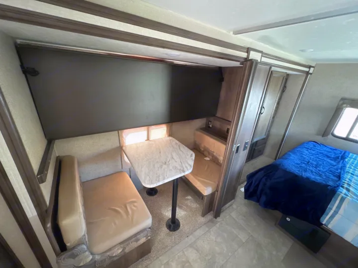 Cozy RV rental interior showcasing a dinette with bench seating, an overhead bunk/storage, and a comfortable bedroom area.. Coachmen Freelancer 2019