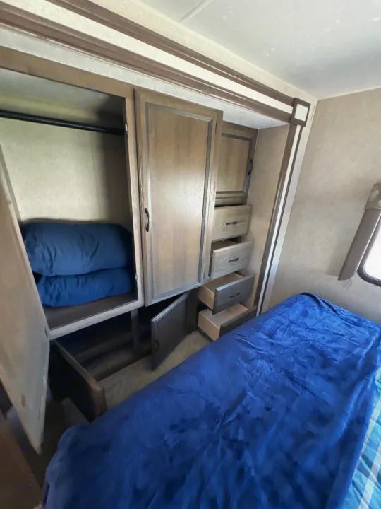 This RV rental bedroom features a cozy bed, a spacious closet with a hanging rod, and multiple built-in drawers for travel storage.. Coachmen Freelancer 2019