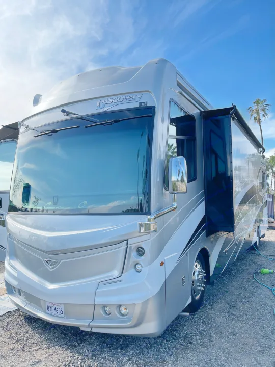 Sleek silver Discovery LXE Class A motorhome, an ideal rv rental. Side slide-out extended, ready for your next trip.. Fleetwood Discovery 2021