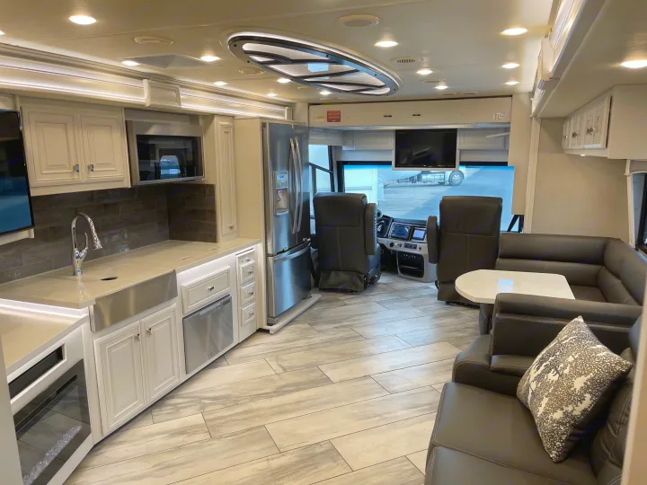 Step inside this luxury RV rental featuring a modern kitchen, comfortable living space, and driver's cockpit for your next adventure.. Fleetwood Discovery 2021
