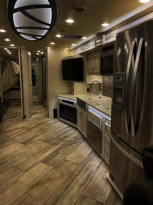 Luxury RV rental: Modern interior featuring a full kitchen with stainless steel appliances, stylish flooring, and spacious design.. Fleetwood Discovery 2021