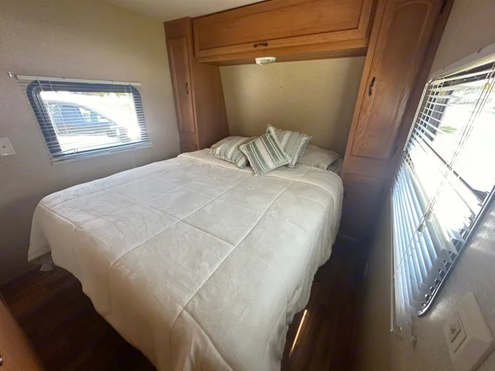 Spacious RV rental bedroom featuring a queen bed, abundant storage, and large windows with blinds. Comfort on the road.. Forest River Salem Cruise Lite 2010