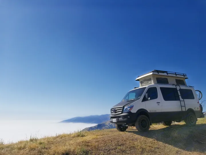White Sportsmobile Sprinter camper van perched above a foggy mountain landscape, ideal for an RV rental adventure.. Sportsmobile Regular Body 4X4 2017