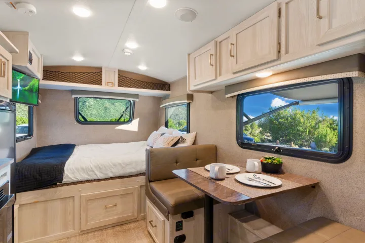 Cozy RV rental interior featuring a comfortable bed, dining area with dinette, and ample storage for your journey.. Rockwood G19QB 2021