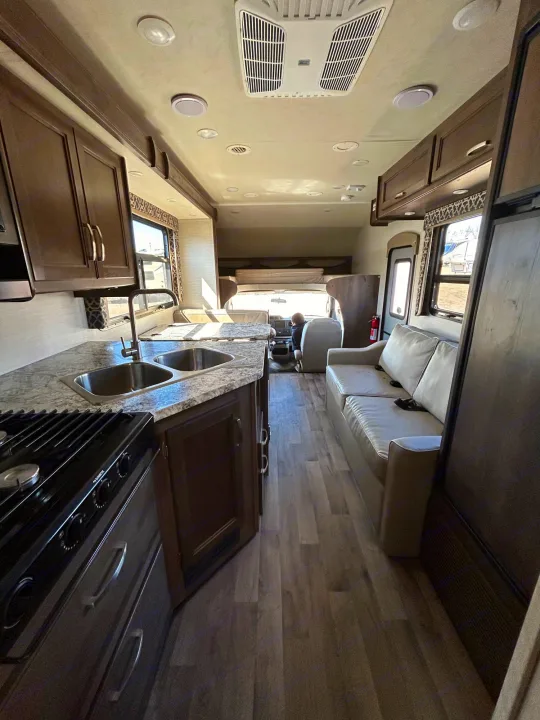 Spacious RV rental interior featuring a modern kitchen, comfortable sofa, and dining area. Ideal for travel.. Redhawk 31F MC 2019