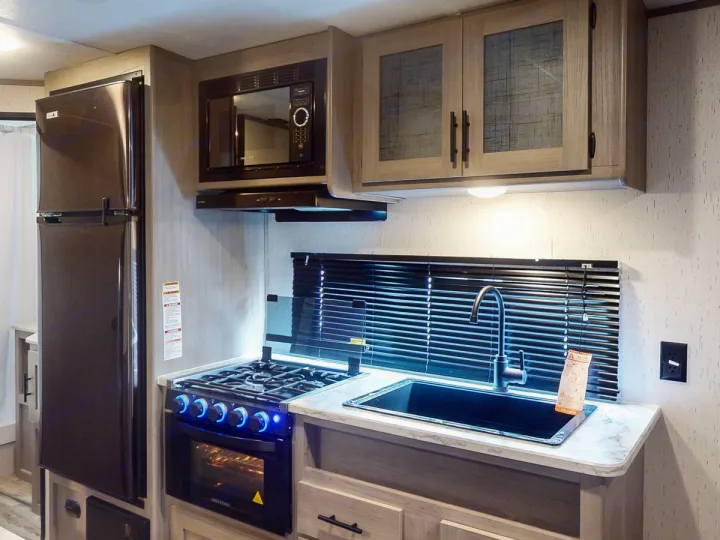 Spacious RV rental kitchen with modern appliances: fridge, microwave, stove, and sink. Perfect for cooking on the road!. Coleman Lantern LT 274BH 2024