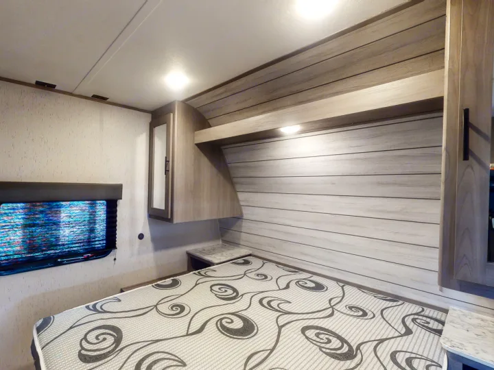 Modern RV rental bedroom featuring a bed, window, and integrated storage, ideal for comfortable travel.. Coleman Lantern LT 274BH 2024