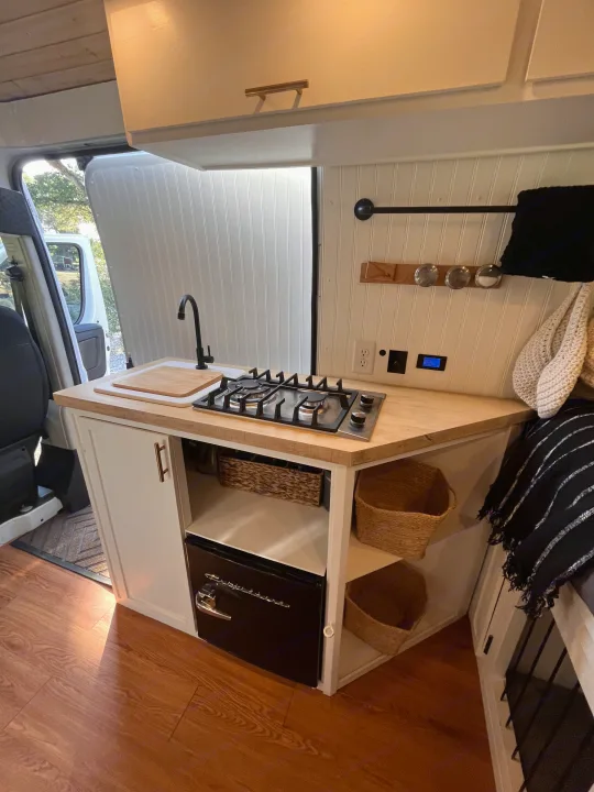 Inside a stylish **rv rental**: a functional kitchen with a sink, stovetop, mini-fridge, and clever storage solutions.. Dodge B Van 2015