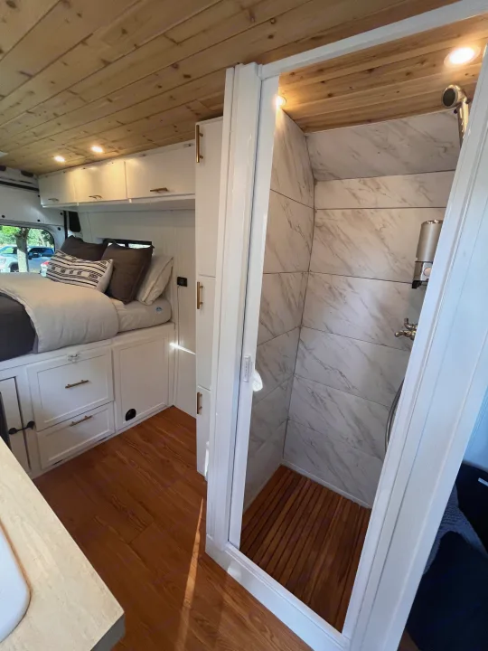 Discover comfort in this RV rental! A cozy bed, wood ceiling, ample storage, and a modern shower with marble-look walls await.. Dodge B Van 2015