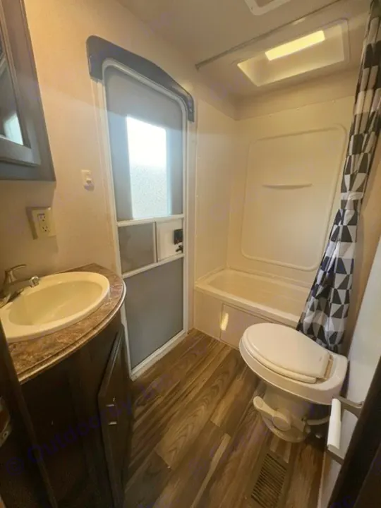 Interior of an RV rental bathroom with a sink, toilet, and shower/tub combo. Wood-look flooring adds comfort.. Forest River Evo 2017