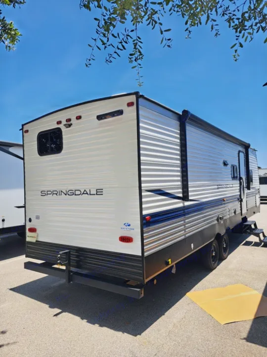 An RV rental: a white Springdale Keystone travel trailer parked outdoors under a bright blue sky.. Keystone RV SG261BHC 2024