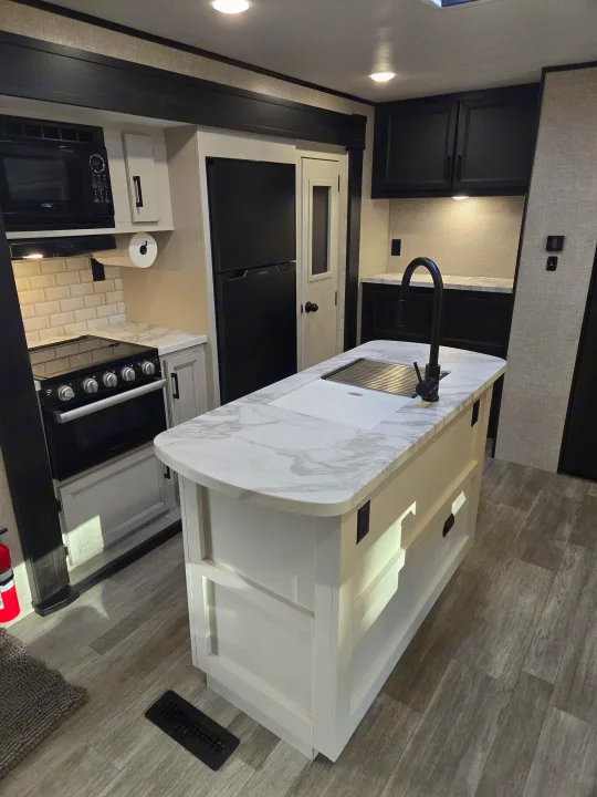 This RV rental boasts a contemporary kitchen with a white island, black appliances, and marble-look counters.. Jayco Jay Flight 2022