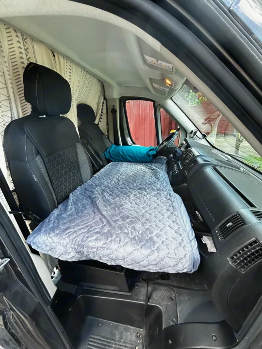 RV rental: Front cabin transformed into a cozy sleeping area. Grey quilted bed extends from seats to dashboard for van travel.. Dodge Ram 1500 2017