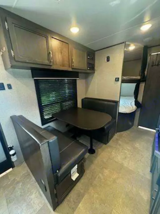 This RV rental offers a spacious interior with a dark dinette, ample overhead cabinets, and a rear bunk bed area.. Jayco Jay Flight SLX 2020