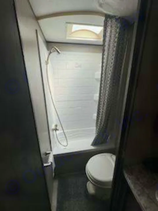 This RV rental bathroom features a bright white shower stall with a skylight on the left, and a toilet on the right.. Jayco Jay Flight SLX 2020
