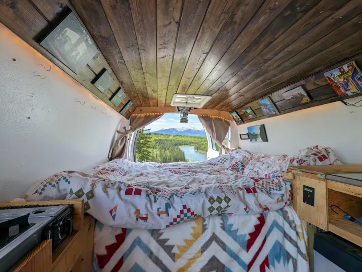 Step inside this RV rental's cozy camper van interior featuring a custom wood ceiling, colorful bedding, and stunning mountain lake views.. Ford Econoline E250supercab 2012
