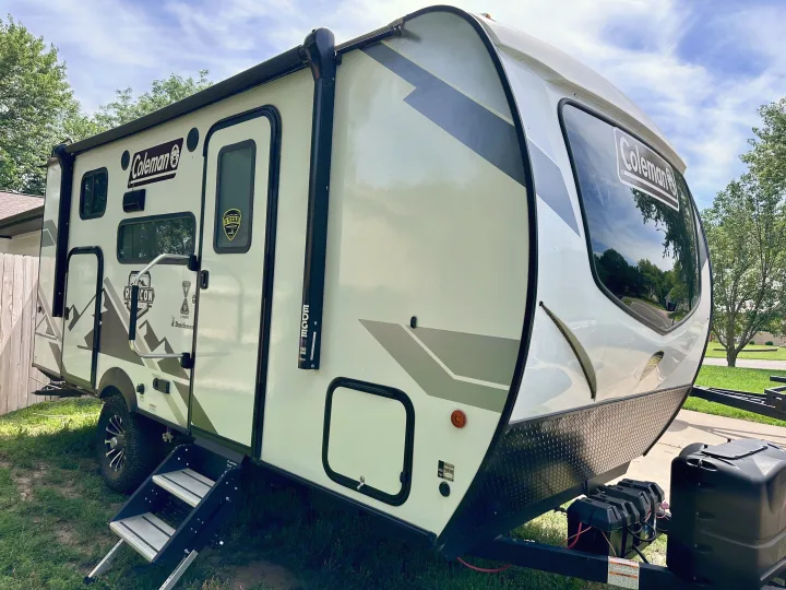 Side view of a white Coleman travel trailer, an ideal rv rental with an awning and steps, ready for adventure.. Dutchmen Coleman Rubicon 2023