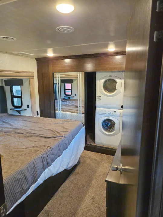 Spacious RV rental bedroom with a comfy bed, mirrored closet, and convenient in-unit washer and dryer.. Cedar Creek Silverback 2020