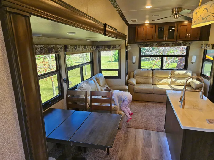 Spacious RV rental interior with a bright living area, kitchen, and a child playing, ideal for family trips.. Cedar Creek Silverback 2020