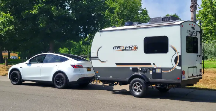 White Tesla Model Y SUV towing a white and gray Geo Pro travel trailer (rv rental). An EV adventure setup.. Forest River Rockwood Geo Pro 2024