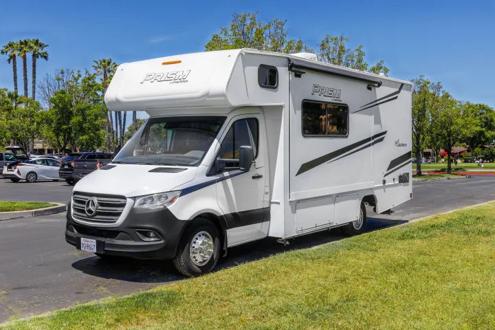 A sleek white Coachmen Prism Class C RV rental, built on a Mercedes-Benz chassis, parked in a sunny lot.. Coachmen Prism 2023