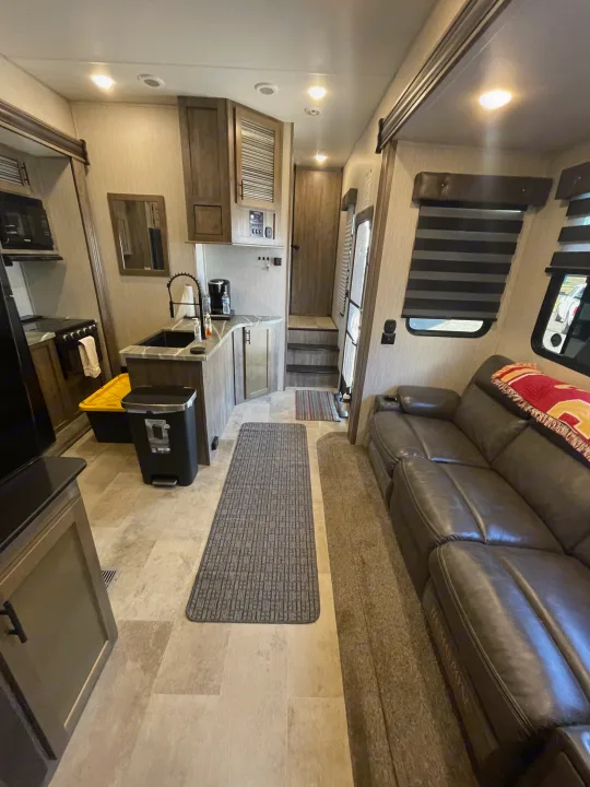 Spacious RV rental interior featuring a modern kitchen, comfortable sofa, and steps to another section.. Forest River Vengeance 2020