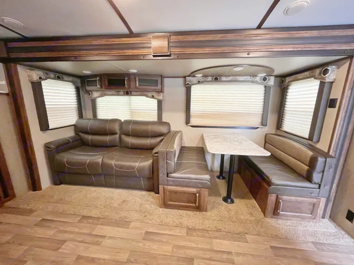 RV rental interior: inviting brown leather sofa, dinette booth, and wood-paneled walls with ample windows.. Keystone RV Cougar X-Lite 2018
