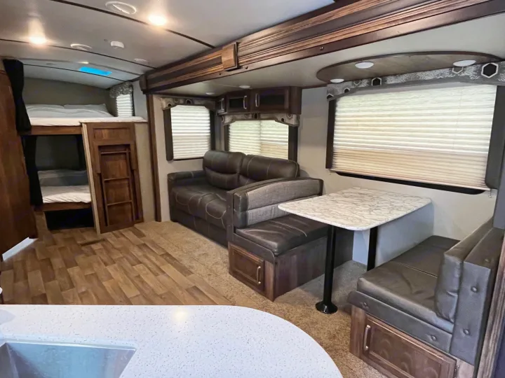 Spacious RV rental interior featuring bunk beds, comfortable sofa, and dinette. Ideal for family road trips.. Keystone RV Cougar X-Lite 2018