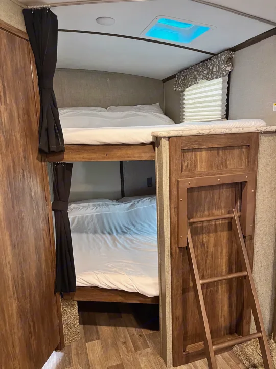 RV rental bunk beds: a neat, space-saving sleeping area with a ladder and privacy curtains, perfect for trips.. Keystone RV Cougar X-Lite 2018