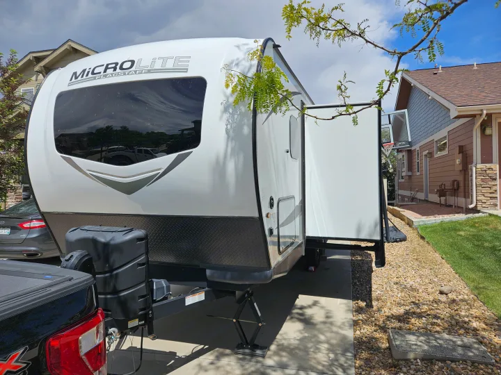 A white MicroLite Flagstaff travel trailer is parked on a driveway with a side slide-out extended. Ideal for an RV rental.. Forest River Flagstaff Micro Lite 2023