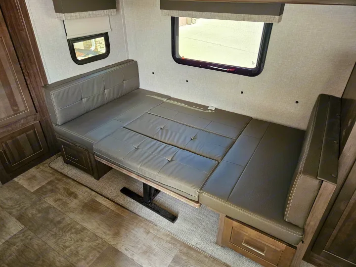 Inside an **RV rental**: a gray upholstered dinette transforms into a bed, complete with windows & under-seat storage.. Forest River Flagstaff Micro Lite 2023