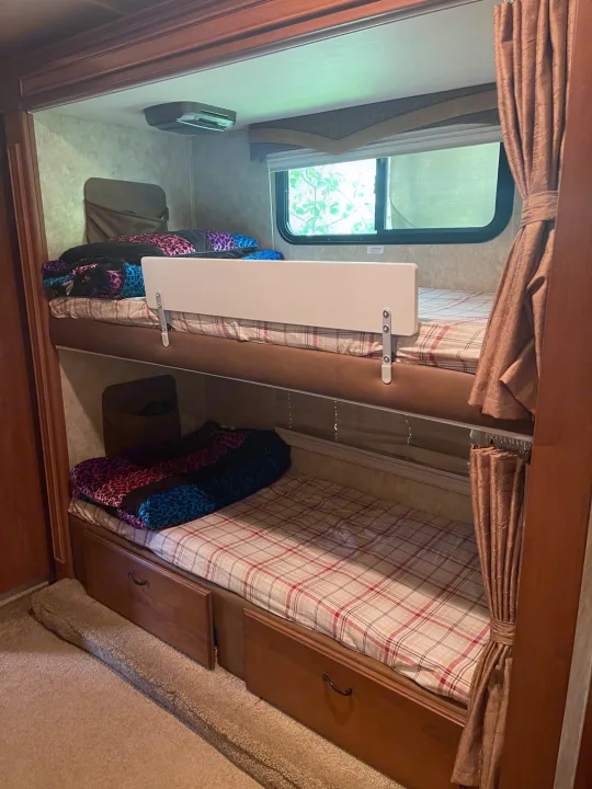 This RV rental features stacked bunk beds with colorful bedding, a safety rail, window, and under-bed storage, ideal for families.. Jayco Greyhawk 2010