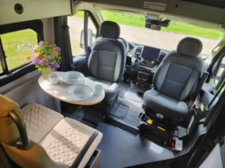 This compact RV rental shows a modern camper van interior with swivel seats and a dining area, perfect for travel.. Winnebago Solis 2023