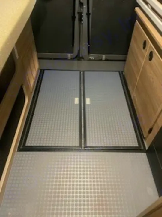 Durable, textured floor and central hinged access hatch inside an RV rental for optimal space use.. Winnebago Solis 2023
