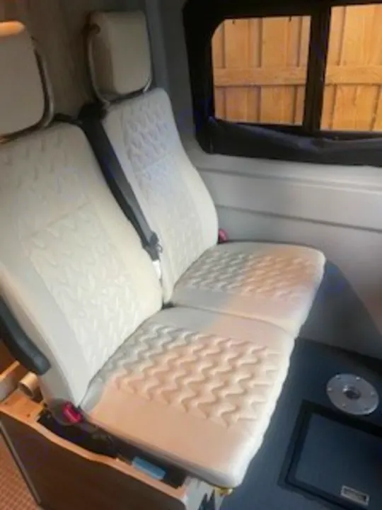 Light-colored, quilted RV rental passenger seating inside a modern van conversion, ready for adventure.. Winnebago Solis 2023