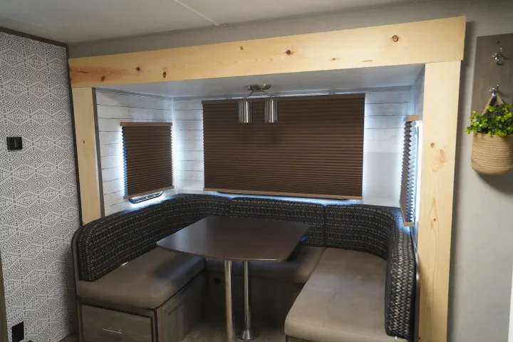 RV rental interior: U-shaped dinette booth, table, brown shades, and natural wood trim.. Forest River Vibe 2020