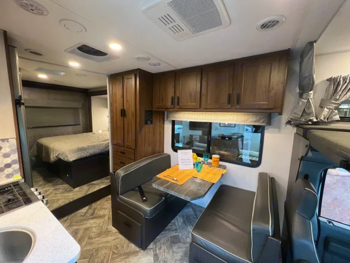 Spacious RV rental interior featuring a bedroom, compact kitchen, dinette, and overhead bunk. Perfect for road trips!. Forester LE 2022