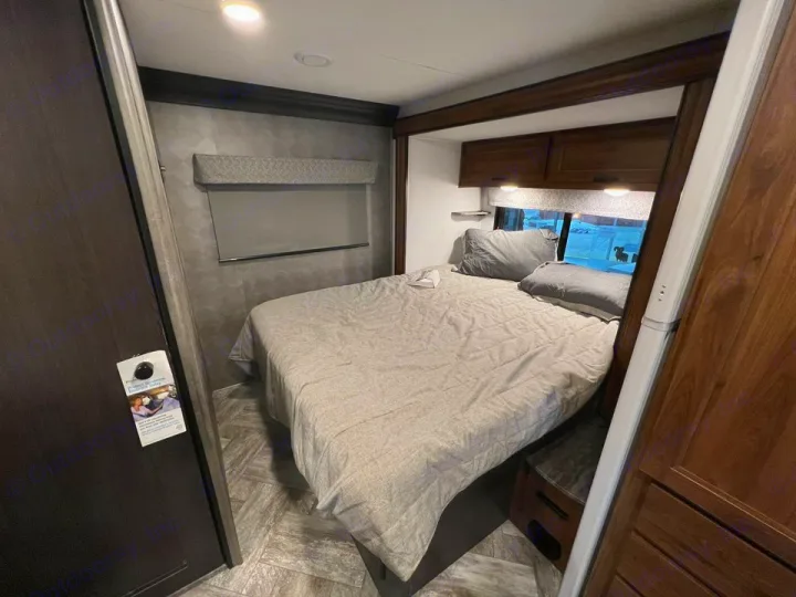 Explore this modern RV rental bedroom interior, featuring a cozy bed, overhead cabinets, and a window view—perfect for travel!. Forester LE 2022