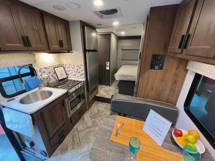 Well-appointed RV rental interior: a compact kitchen, dining nook, and a peek into the bedroom for mobile living.. Forester LE 2022