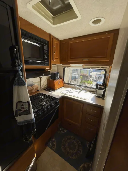 Functional RV rental kitchen: microwave, stove, sink, and coffee maker in a compact layout for travel.. Jamboree Jamboree Motorhome 2006