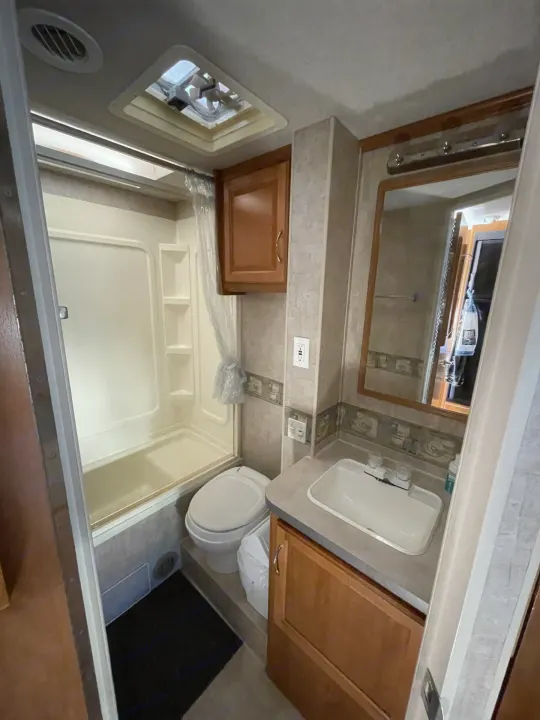 RV rental bathroom with tub/shower combo, toilet, and vanity with sink/mirror. Clean, functional interior.. Jamboree Jamboree Motorhome 2006