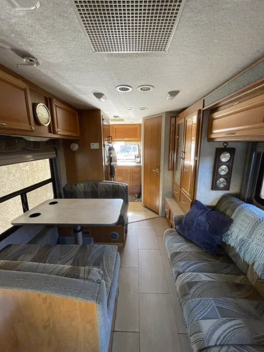Spacious RV rental interior featuring a cozy dining booth, kitchen, living area, and ample wooden cabinets.. Jamboree Jamboree Motorhome 2006