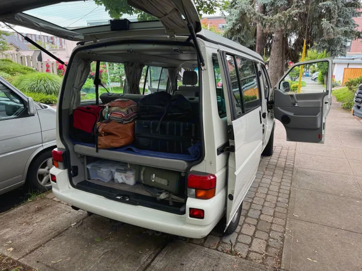 White camper van being packed, rear hatch open with luggage, side door open. Perfect for an RV rental adventure!. Volkswagen Westfalia 2003